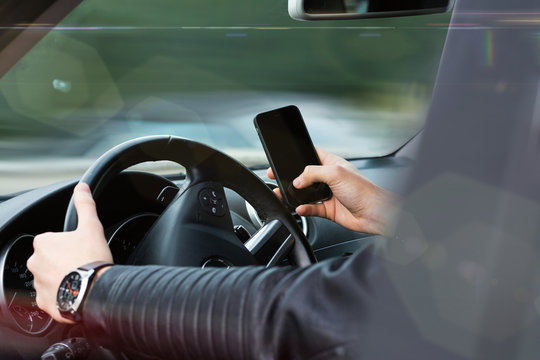 Hands using steering wheel and phone