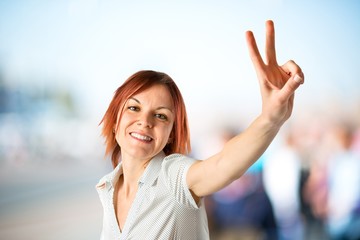 Young woman doing victory gesture over white background