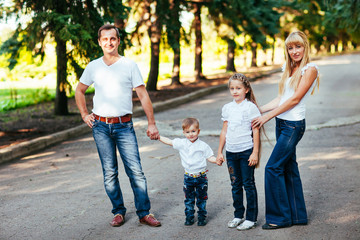 Fototapeta na wymiar Happy young family walking down the road outside in green nature