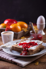 Toast with plum jam and cottage cheese on a white plate on an autumn background.