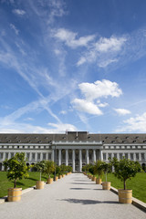 A huge building in Germany. The blue sky has some clouds and airplane trails.