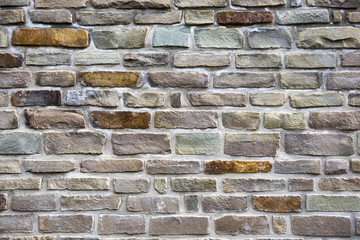 A brick wall. The wall is made of different colors of bricks or stones.