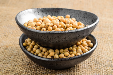 soybeans in ceramic bowl on sackcloth background..