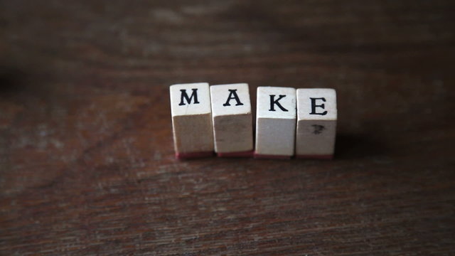 stop motion of an optimistic sentence "make it real" with alphabet stamp, indoor