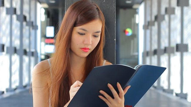 Portrait of thai adult beautiful girl Read and think in university.