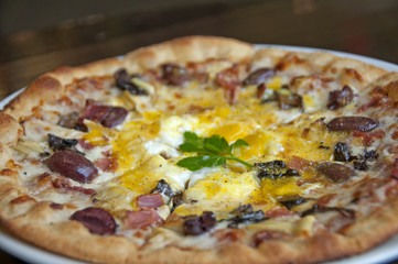 gourmet pizza with olives, ham and egg on top
