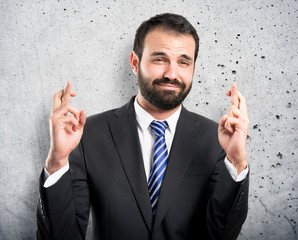 Young businessman with his fingers crossing over white backgroun