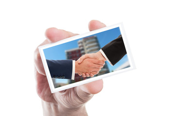 Hand holding card with real estate or business handshake