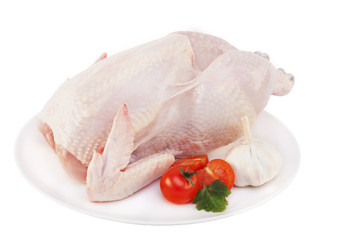 Сырая куриная тушка с томатами и зеленью на тарелке без фона