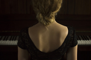 Fototapeta premium Young beautiful girl playing on the piano
