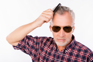 Gray aged man with sunglasses combing his  hair