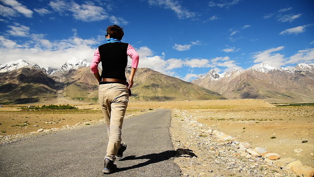 Smart Asian woman covered her face walking on lonely road in sunny day, Padum, Zanskar valley, India 