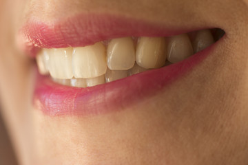 Macro shot of female smile with teeth and pink lipstick