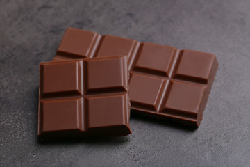 Milk chocolate pieces on gray background