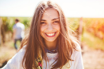 Smiling teenage girl outdoors on sunny day. Closeup of cute brunette young woman wearing casual...