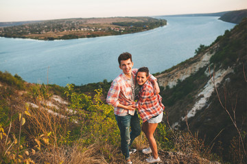 Naklejka premium Young couple in love outdoor. Portrait of a happy couple hugging on nature with river background.