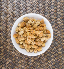 Dried white mulberry in a white bowl over wicker background