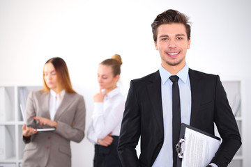 Cheerful business man in office with colleagues in the background, sturt  up team