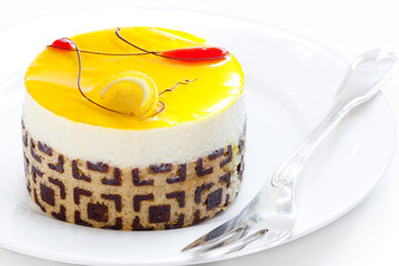 Lemon mousse individual serving cake on white plate with silver fork