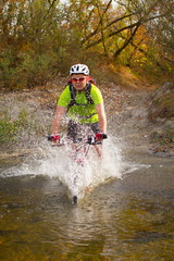 Young athlete crossing rocky terrain with bicycle in his hands.