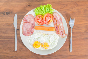 English breakfast with fried eggs, bacon, sausages, ham and fres