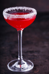 Red alcoholic cocktail  in a glass on a black background.
