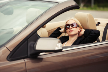 Young fashion woman in sunglasses in a convertible car