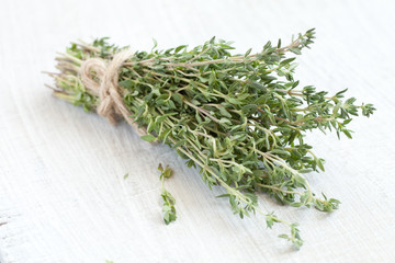 bundle of thyme on a white wooden background