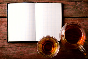 Open blank notepad on old wooden table with tea