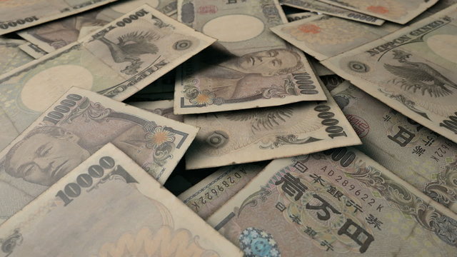 An extreme close up pan of a pile of randomly scattered japanese yen banknotes