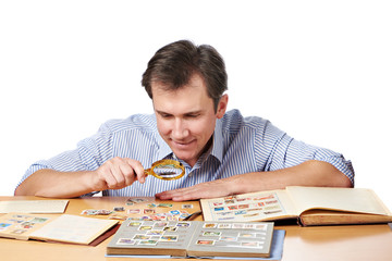 Man watching a collection of postage stamps with magnifier