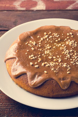 Pumpkin cake with caramel and peanuts on wooden table
