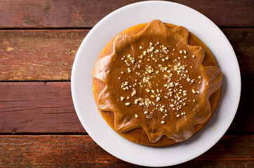 Pumpkin cake with caramel and peanuts on wooden table