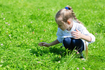 Girl catching a grasshopper in the grass