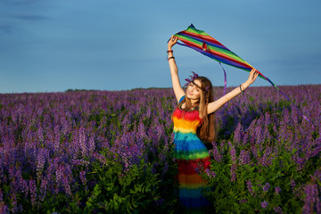 young woman in a rainbow dress and a rainbow kite outdoors