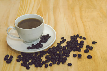 Cup of coffee with coffee beans on wood floor