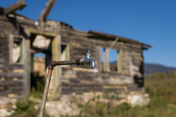 Broken water tap with abandoned building background