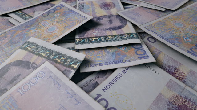 An extreme close up pan of a pile of randomly scattered norwegian kroner banknotes
