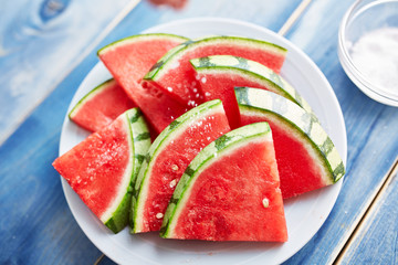 sprinkling salt on a pile of watermelon slices © Joshua Resnick
