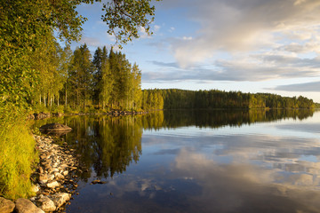 Obraz premium Amazing sunset scenery from Finland. The colorful forest makes a beautiful reflections on the still water surface