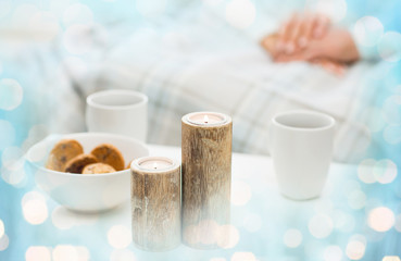 close up of candles, cookies and tea cups on table