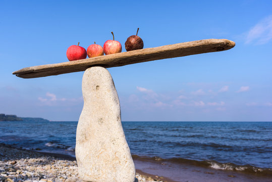 Apples in balance on narrow plank