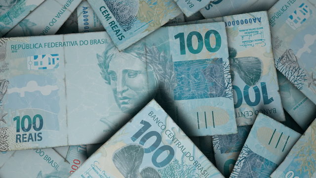 An extreme close up pan of a pile of randomly scattered brazilian real banknotes