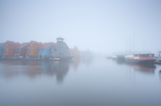 colorful building on water and boats in fog
