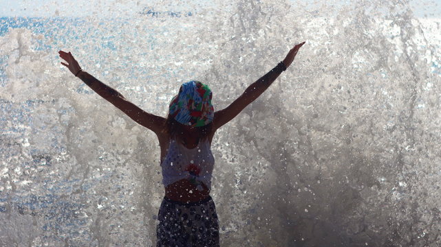 Girl on the beach with wave splash