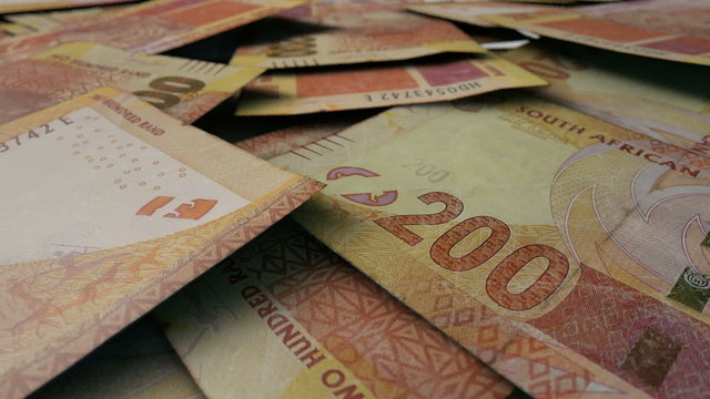 An extreme close up pan of a pile of randomly scattered south african rand banknotes