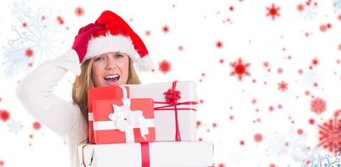 Composite image of festive blonde holding pile of gifts