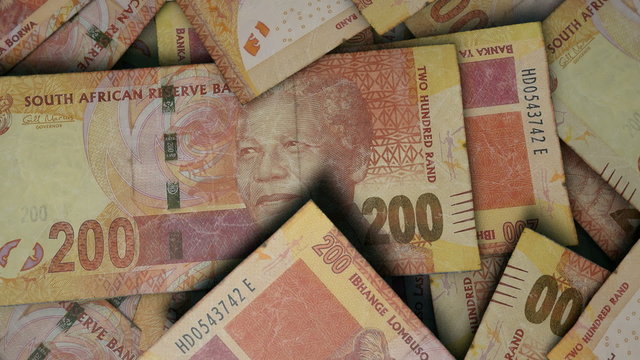 An extreme close up pan of a pile of randomly scattered south african rand banknotes