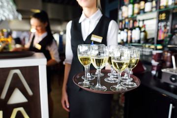 Waitress with dish of champagne and wine glasses
