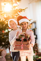 Christmas morning, two  kids near xmas tree, arms full of gifts